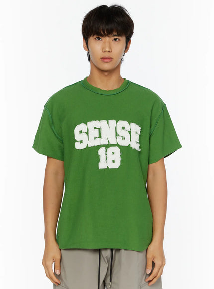 Men's Graphic Slogan T-Shirt IL509 Green close-up front shot on male model highlighting SENSE 18 white flocked logo raw-cut sleeves and frayed neckline detail