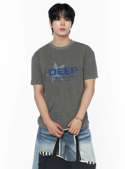 Men's Graphic Star T-Shirt IU523 Gray front crop shot on male model holding tote bag, blue DEEP BREATHE SLOW star graphic, white contrast stitching