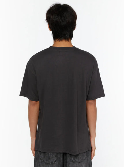 Men's Graphic T-Shirt IL515 Charcoal back view on male model, plain clean back panel, relaxed oversized cotton construction, styled with wide-leg denim