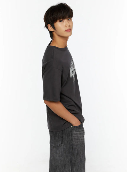 Men's Graphic T-Shirt IL515 Charcoal side view close-up on male model looking upward, hands in pockets, distressed gothic graphic visible on chest