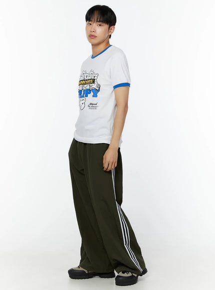 Men's Graphic T-Shirt IU529 white side view on male model angled pose blue ringer collar and cuffs SUNNYDAYS HAPPY bear graphic print styled with olive wide-leg track pants