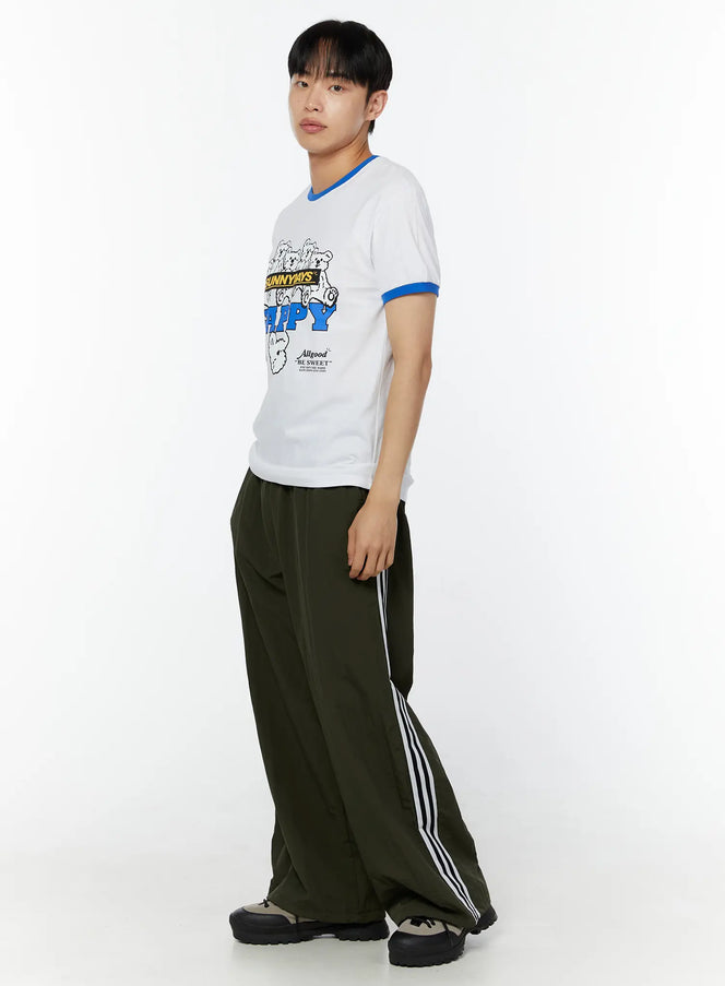 Men's Graphic T-Shirt IU529 white side view on male model angled pose blue ringer collar and cuffs SUNNYDAYS HAPPY bear graphic print styled with olive wide-leg track pants