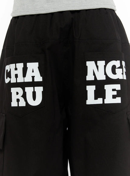 Men's Graphic Wide Jorts IL510 Black close-up detail of rear waistband and back cargo pockets with white CHA RU NGLE LE graphic print