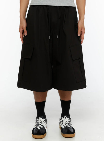 Men's Graphic Wide Jorts IL510 Black front close-up on model showing drawstring elastic waistband and oversized double cargo pockets