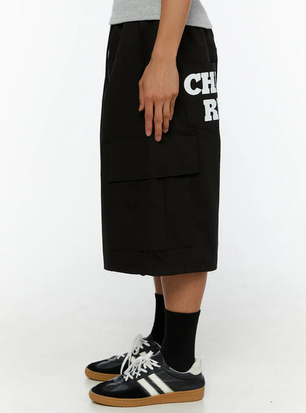 Men's Graphic Wide Jorts IL510 Black left side view on model showing CHA RU white graphic print on cargo pocket with wide leg silhouette