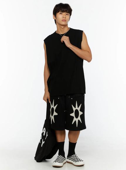 Men's Happy Sun Jorts IL510 Black full front view on male model styled with black sleeveless top, dual cream sun appliqué on wide-leg shorts above the knee