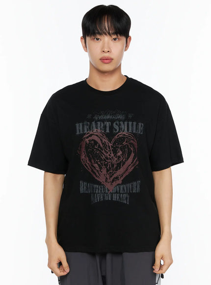 Men's Heart Graphic Tee IL514 Black front close-up shot on male model showing dark-toned grunge HEART SMILE graphic print with burgundy brushstroke heart on heavyweight cotton tee