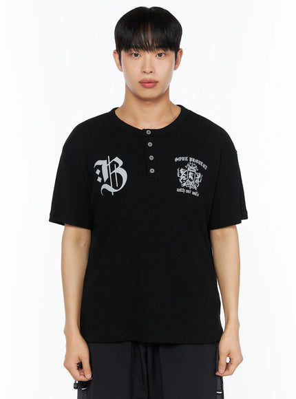 Men's Henley Waffle Tee IL514 Black front shot on male model showing gothic B and crest graphic print ribbed waffle knit fabric and henley button placket