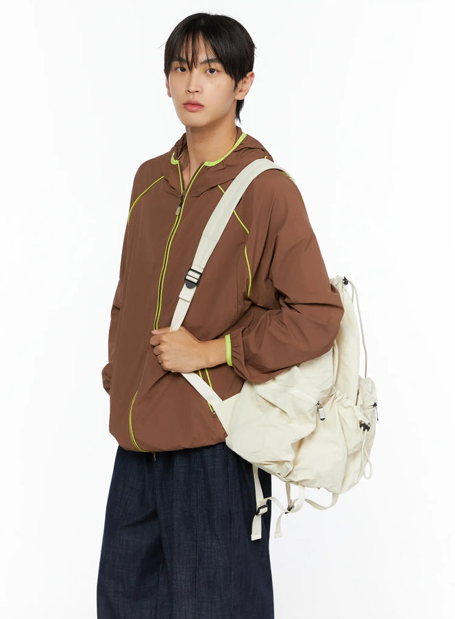 LEWKIN Men's Hooded Windbreaker IL528 Brown M/L three-quarter shot on model carrying cream backpack, neon yellow piping and hood trim, lightweight nylon