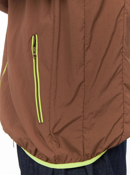 Men's Hooded Windbreaker IL528 Brown close-up detail of neon yellow zip side pocket, perforated nylon fabric texture, and elasticated hem trim