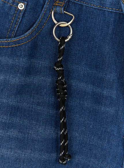 Men's Keyring Detail Jorts IL515 blue close-up detail flat shot of silver spring-ring hardware and knotted black reflective rope charm on washed indigo denim fabric