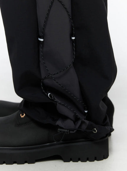 Men's Lace-Up Track Pants (Black) IL514 Black close-up detail of hem and ankle area showing open lace-up panel, drawstring hem adjuster, and chunky black boot