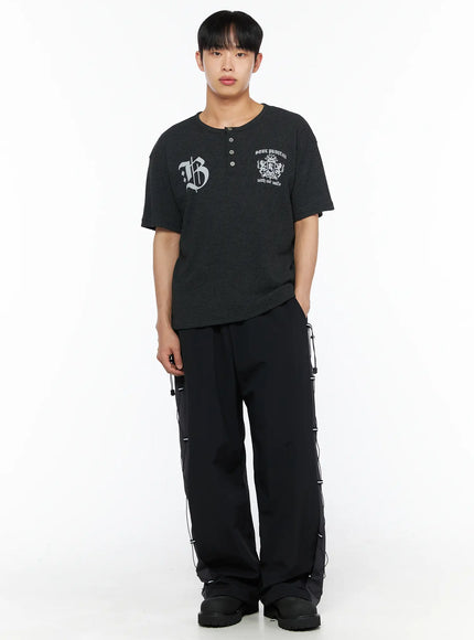 Men's Lace-Up Track Pants (Black) IL514 Black full-length front shot on male model styled with dark graphic henley tee, hands at sides, showing wide-leg silhouette