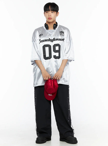 Men's Lace-Up Track Pants (Black) IL514 Black full-length front shot on male model styled with silver football jersey, red cap, and headphones held at waist