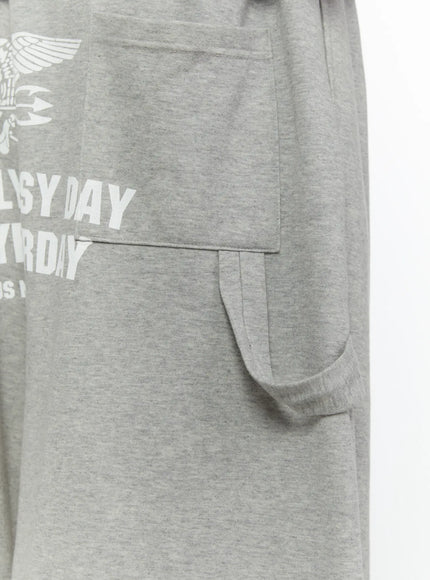 Men's Lettering Bermuda Shorts IL513 Gray close-up detail of side cargo pocket and tab closure, heather gray marl cotton fabric texture, partial back lettering graphic visible