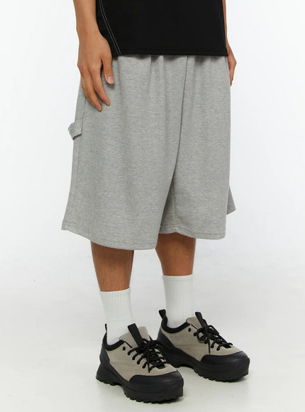 Men's Lettering Bermuda Shorts IL513 Gray front close-up on male model, elastic ruched waistband detail, heather gray cotton fabric, wide flared leg opening, side cargo pocket visible