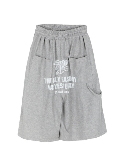 Men's Lettering Bermuda Shorts IL513 Gray flat-lay front view, US Navy Seals eagle and lettering graphic print on front panel, two patch pockets, side cargo tab pocket, elastic waistband