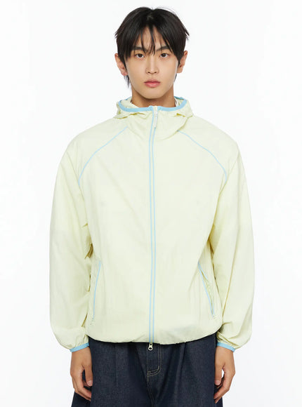 Men's Lightweight Windbreaker IL528 Light yellow front upper-body on model showing zip-up front, hooded collar with blue trim detail