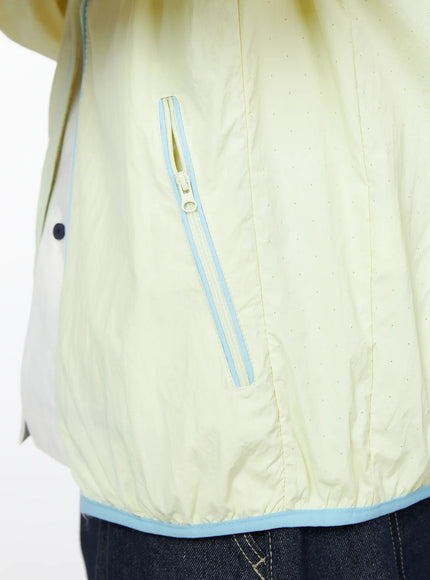 Men's Lightweight Windbreaker IL528 Light yellow close-up detail of angled side zip pocket with blue contrast piping and perforated nylon fabric