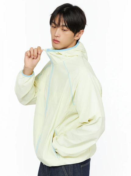 LEWKIN Men's Lightweight Windbreaker IL528 Light yellow side-angle detail on model pulling zipper, blue contrast piping, nylon shell, M/L