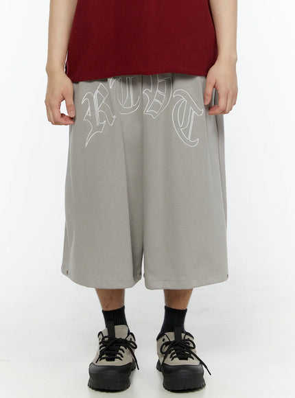 LEWKIN Men's Logo Embroidered Snap Hem Bermuda Sweat Shorts (Gray) IL507 gray front view on model cropped waist-down with wide-leg silhouette and old-English logo print