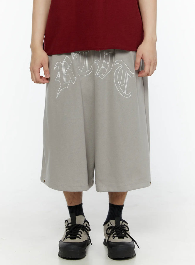 LEWKIN Men's Logo Embroidered Snap Hem Bermuda Sweat Shorts (Gray) IL507 gray front view on model cropped waist-down with wide-leg silhouette and old-English logo print