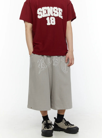 Men's Logo Embroidered Snap Hem Bermuda Sweat Shorts (Gray) IL507 gray three-quarter front view on model styled with burgundy SENSE 18 tee showing full logo print