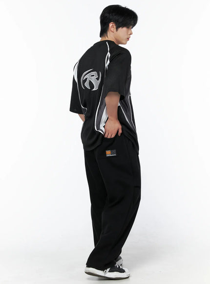 Men's Mesh Contrast V-Neck T-Shirt IU523 Black three-quarter back side shot on male model showing back logo and contrast panel detail with black wide-leg trousers