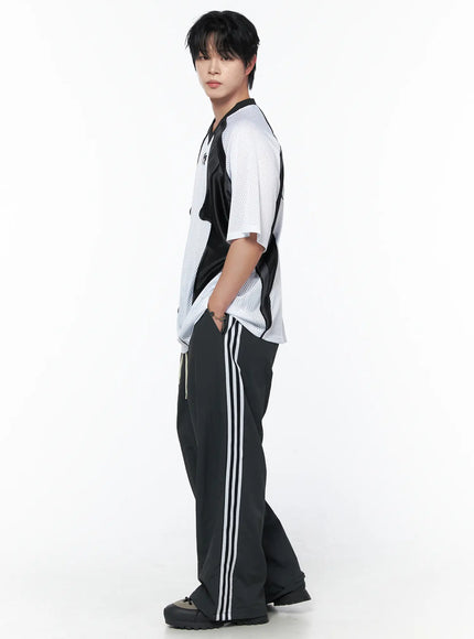 Men's Mesh Contrast V-Neck T-Shirt IU523 White side shot on male model showing raglan sleeve structure and black contrast panel depth with stripe track trousers