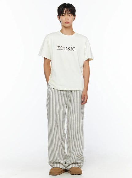 Men's Music Print T-Shirt IL515 ivory full-body front shot male model hands in pockets standing upright showing complete outfit with striped pants and tan shoes