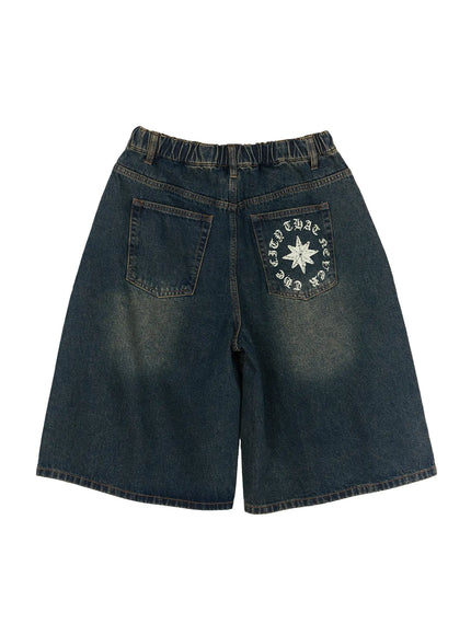 Men's 'Never Stop' Graphic Bermuda Jorts (Blue) IL507 flat-lay back view, showing dual back pockets with star compass circular graphic print on right pocket and washed denim fade texture