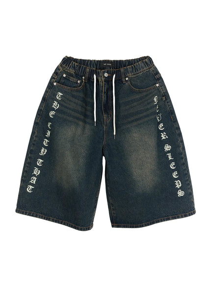 Men's 'Never Stop' Graphic Bermuda Jorts (Blue) IL507 flat-lay front view, dark washed indigo denim with old english vertical letter graphics on both legs, elastic drawstring waistband