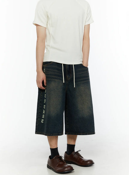 Men's 'Never Stop' Graphic Bermuda Jorts (Blue) IL507 full front view on model styled with white ribbed tee and brown leather shoes, wide-leg silhouette with drawstring waist