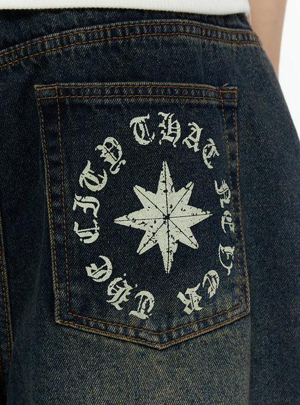 Men's 'Never Stop' Graphic Bermuda Jorts (Dark Blue) IL507 close-up of back pocket with distressed star compass and circular old English gothic text graphic