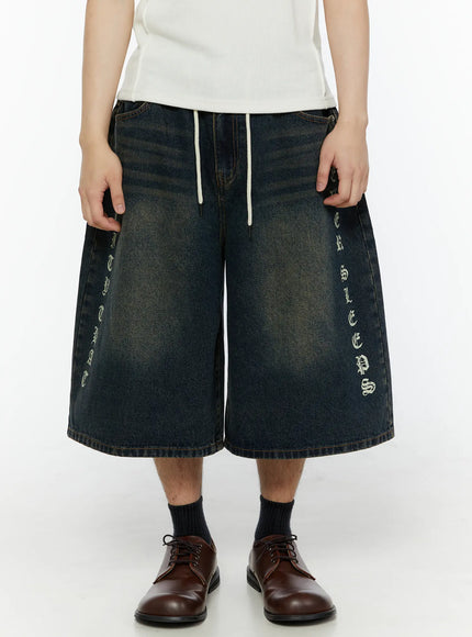 LEWKIN Men's 'Never Stop' Graphic Bermuda Jorts (Dark Blue) IL507 front view on model with old English vertical letter print and white drawstring waist