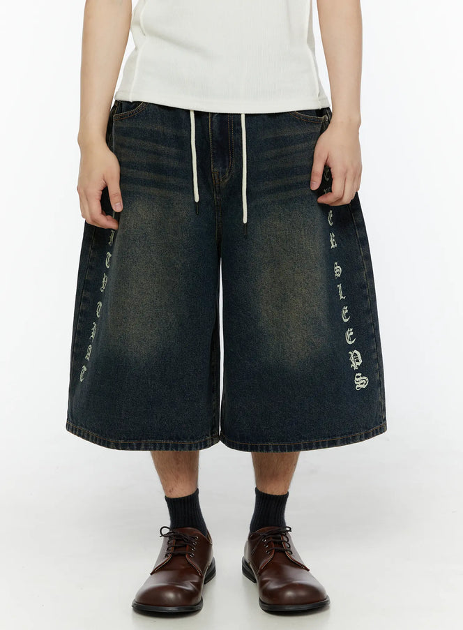 LEWKIN Men's 'Never Stop' Graphic Bermuda Jorts (Dark Blue) IL507 front view on model with old English vertical letter print and white drawstring waist