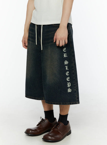 Men's 'Never Stop' Graphic Bermuda Jorts (Dark Blue) IL507 side view on model showing vertical old English letter graphic and white drawstring waistband detail