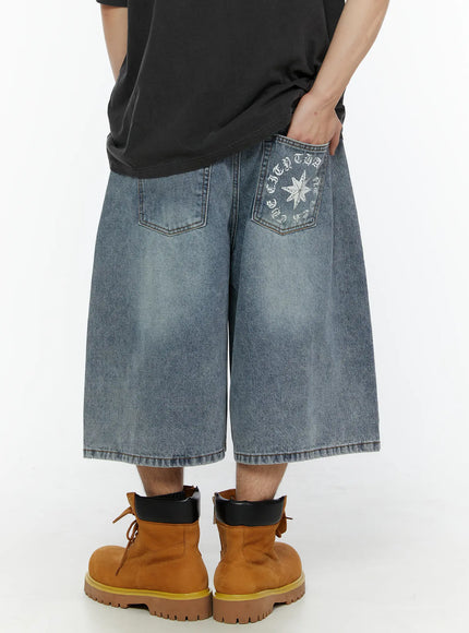 Men's 'Never Stop' Graphic Bermuda Jorts (Light Blue) IL507 back view on model, wide-leg denim bermuda shorts showing star graphic on right back pocket, elastic waistband, styled with tan boots