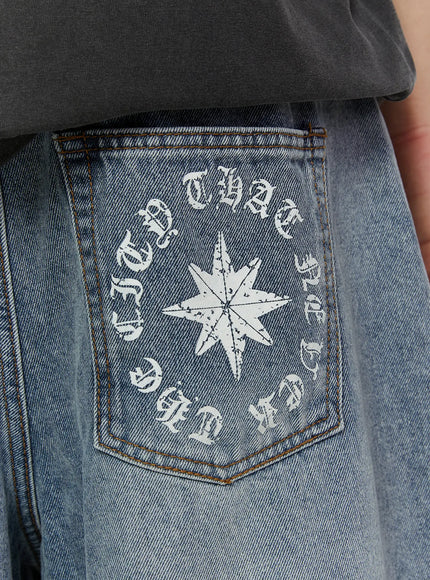 Men's 'Never Stop' Graphic Bermuda Jorts (Light Blue) IL507 close-up detail of right back pocket, old-english circular text and distressed eight-point star graphic print on washed light blue denim
