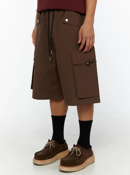 Men's Nylon Cargo Drawstring Bermuda Shorts (Dark Brown) IL507 Dark brown side close-up on model highlighting right cargo pocket with toggle clasp and snap front pocket