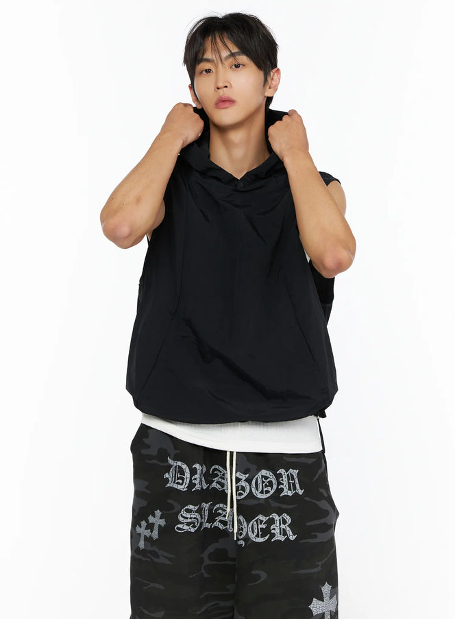 Men's Nylon Hooded Vest IL520 Black close-up front shot on male model gripping hood with both hands, layered over white top