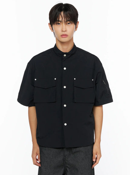 Men's Nylon Utility Shirt IL515 Black front close-up shot on model showing band collar, dual chest flap pockets, silver snap button placket, and sleeve zipper detail