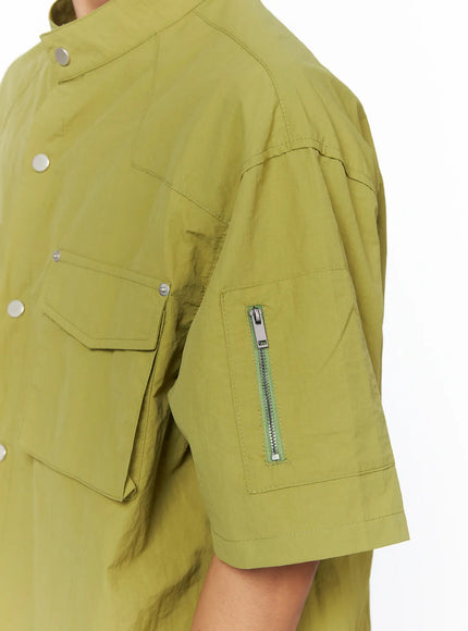 Men's Nylon Utility Shirt IL515 Olive Green close-up side detail shot on model showing sleeve zipper pocket and cargo-style flap pocket with crinkled nylon texture