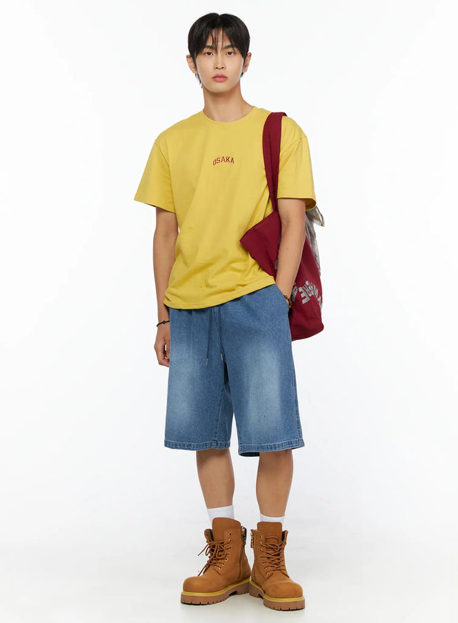 LEWKIN Men's Osaka Graphic T-Shirt IL520 Yellow full-body front shot on model styled with denim shorts, tan boots, and burgundy tote bag, S/M