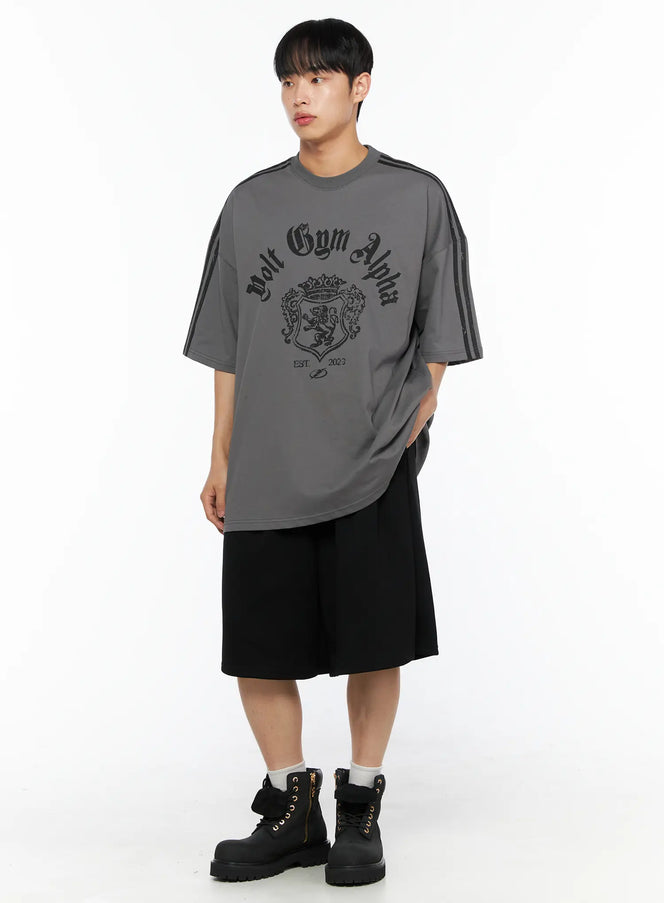 Men's Oversized Athletic Tee IL514 Gray full-body front shot on male model styled with black wide shorts and boots, oversized silhouette with tonal crest graphic