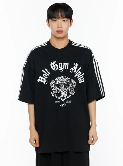 Men's Oversized Athletic Tee IL514 Black close-up front shot on male model from waist up, white gothic Volt Gym Alpha crest print and white stripe sleeve detail clearly visible