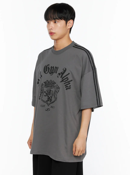 Men's Oversized Athletic Tee IL514 Gray side shot on male model showing angular three-quarter angle, black stripe sleeve and Volt Gym Alpha gothic graphic on chest