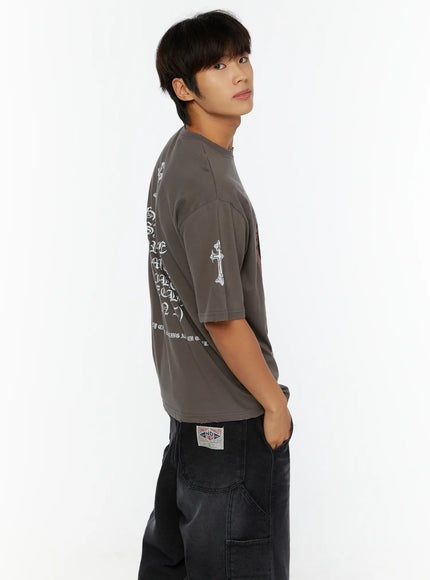 Men's Oversized Graphic T-Shirt IL513 charcoal gray side back model shot revealing gothic old English back text print and cross detail on sleeve
