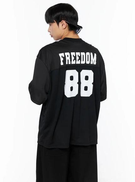 Men's Oversized Mesh Rugby Tee IL514 Black back three-quarter shot on male model with sunglasses, white FREEDOM 88 varsity print, mesh upper panel, oversized boxy fit with black pants