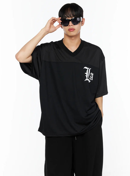 LEWKIN Men's Oversized Mesh Rugby Tee IL514 Black front shot on male model wearing sunglasses, V-neck with panel seam, white La gothic logo, paired with black pants